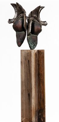 une sculpture représentant une paire de chaussures posée sur un bloc de bois