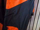 un sac à dos orange et noir posé sur une étagère à côté d'une paire de chaussures