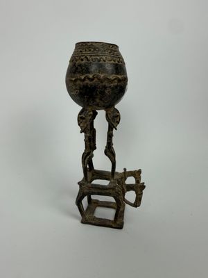 un vieux vase en bronze posé sur un socle et orné d'un oiseau