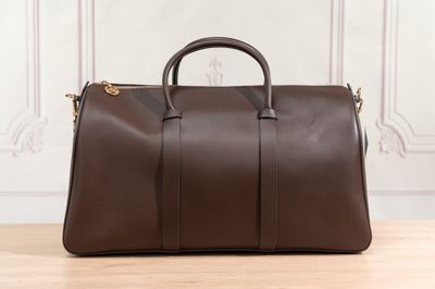 un sac de voyage en cuir marron posé sur une table en bois