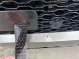someone is measuring the width of a car ' s grille with a ruler
