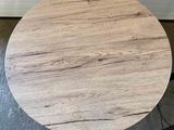 a small round table with a wooden top on a concrete floor