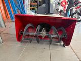 a red snow blower sitting on the ground in a garage
