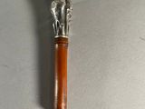 une petite brosse en argent et en bois posée sur une surface blanche
