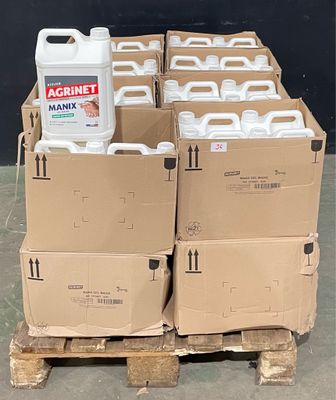 Plusieurs conteneurs remplis de liquide sont posés sur des palettes devant un mur noir
