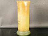 a yellow vase sitting on a table with a black surface