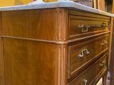 a wooden dresser with a marble top and two candles on it