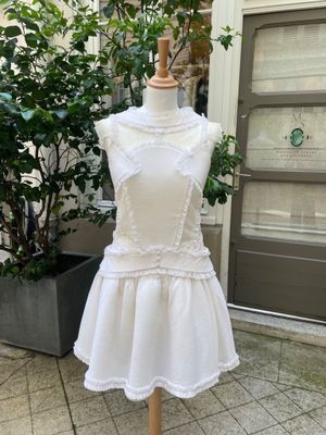 white dress on a mannequin with a potted plant in the background