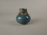 a small blue vase with a gold decoration on it