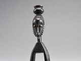 une sculpture noire représentant une femme dont la tête repose sur une fourchette