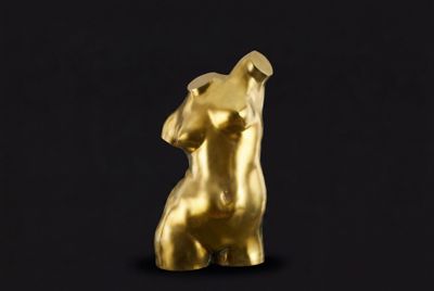 une statue en or représentant une femme sur fond noir