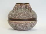 a brown and white vase sitting on a white surface
