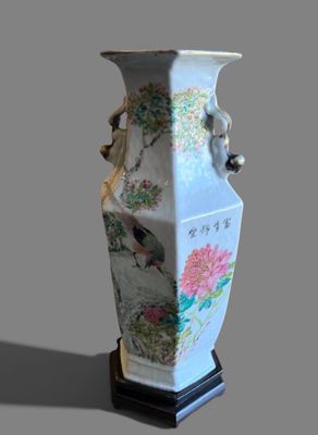 a vase that has a bird on it on a stand