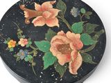 a black box with flowers painted on it on a white surface