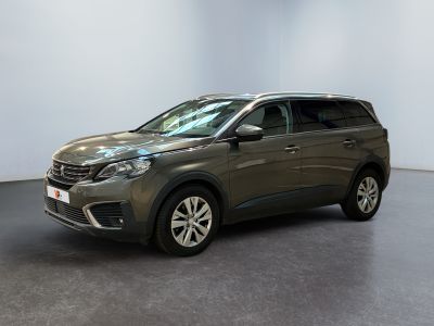 Une voiture grise est garée dans une pièce aux murs blancs.