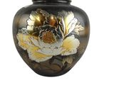 un vase noir orné de fleurs dorées et blanches