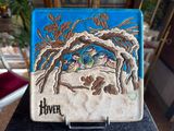 a tile with a picture of a bird and a tree on it