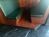 une cabine avec un siège vert et une table en bois