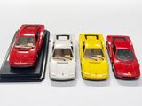 quatre petites voitures sont alignées sur une surface blanche