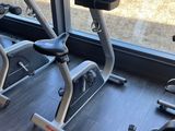 two stationary exercise bikes in a gym room with a large window