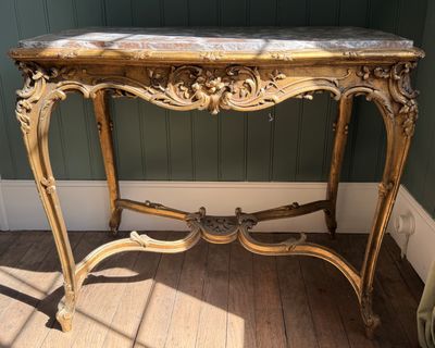 une petite table avec un plateau en marbre sur un plancher en bois