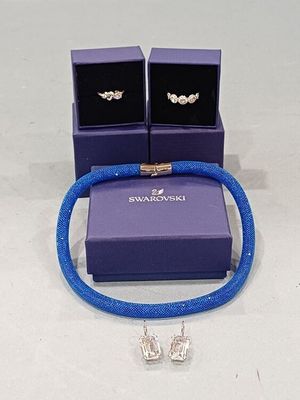 boîte à bijoux violette contenant deux boucles d'oreilles en argent et un bracelet bleu