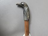 a metal bird on a wooden stick on a gray surface