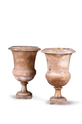pair of large stone urns on pedestals against a white background