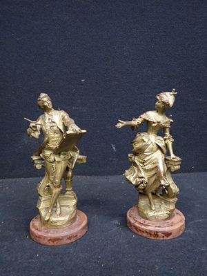 pair of antique bronze figurines of a woman and a man on a horse