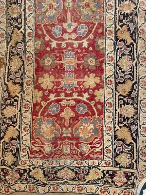 an antique rug with a red background and a gold border
