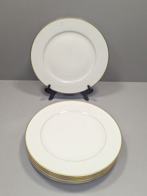 deux assiettes blanches aux bords dorés reposent sur une surface grise