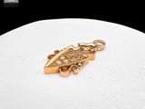 a close up of a gold pendant on a white surface