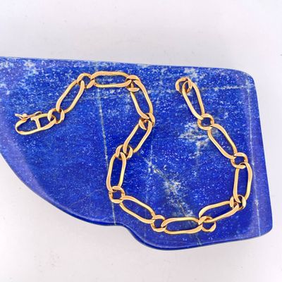 blue and gold necklace with a gold chain on a blue plate