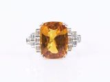 a close up of a ring with a large citrine stone surrounded by diamonds