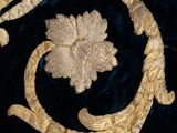 a close up of a black and gold table cloth with flowers on it