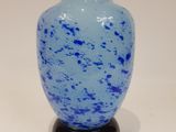 a blue vase sitting on a black stand on a white surface