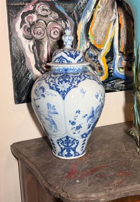 deux vases posés sur une table devant un tableau