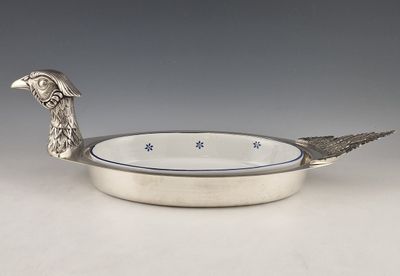 un plateau en argent orné d'un oiseau, posé sur une table