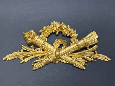 une image représentant une broche plaquée or ornée d'une couronne de fleurs et de feuilles