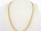 a gold necklace with a twisted rope design on a mannequin neck