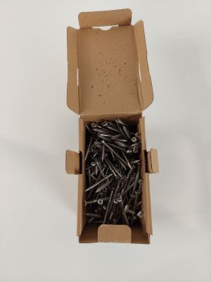 une boîte remplie de vis posée sur une surface blanche