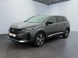Une voiture grise est garée dans une pièce blanche au sol noir.