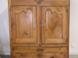 a wooden armoire with a vase on top of it
