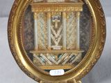 une photo d'une horloge miniature exposée dans un cadre doré