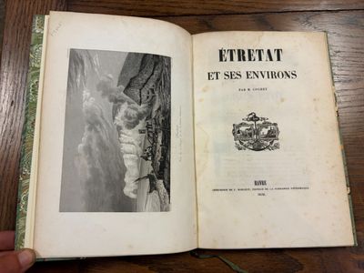 Quelqu'un tient un livre ouvert sur une table sur laquelle est posée une photo de chat.