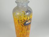 yellow and blue vase sitting on a white surface with a white background