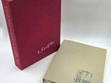 an open book with a red cover sitting on top of a white table