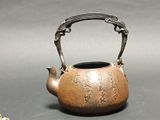 a small tea pot with a handle on a table