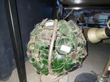 une boule de verre verte posée par terre à côté d'un poteau métallique