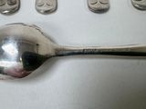 a spoon with a face on it next to five spoons and a spoon with a face on it